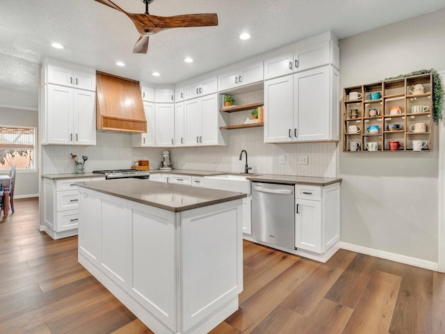 kitchen with a kitchen island, white cabinets, stainless steel dishwasher, custom exhaust hood, and open shelves