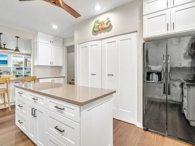 kitchen featuring decorative light fixtures, black fridge with ice dispenser, white cabinetry, ceiling fan, and light wood-type flooring