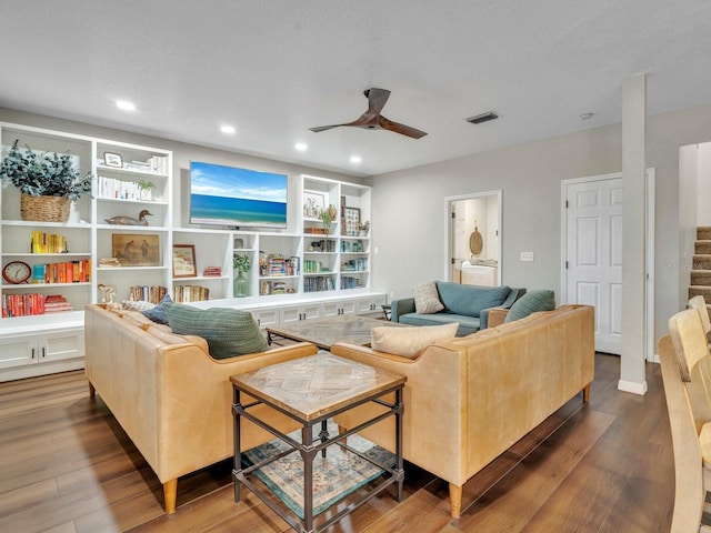 living room with stairway, a ceiling fan, visible vents, and dark wood-type flooring