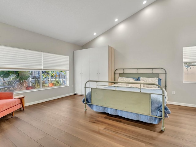 bedroom with high vaulted ceiling, recessed lighting, light wood-style flooring, and baseboards