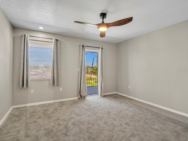 spare room featuring baseboards, ceiling fan, a textured ceiling, and light colored carpet