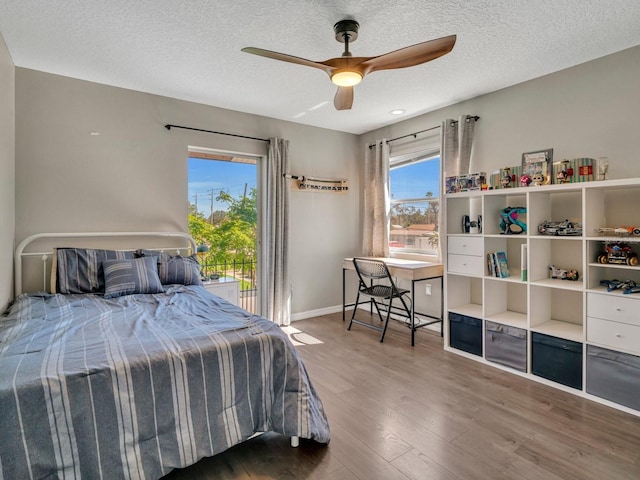 bedroom featuring a textured ceiling, multiple windows, wood finished floors, and baseboards