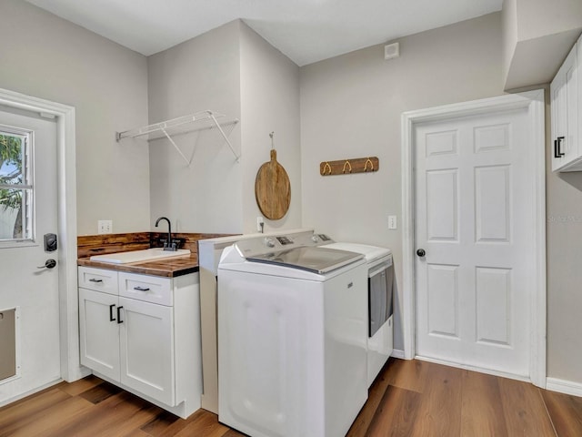 laundry room with light wood finished floors, a sink, cabinet space, and washer and dryer