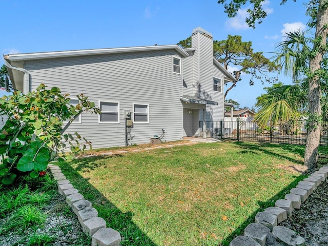 rear view of house with a yard, a chimney, and fence