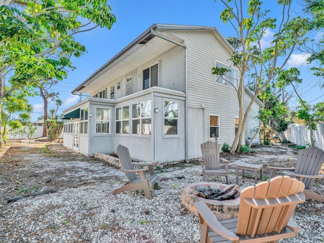 back of property with a fire pit and fence