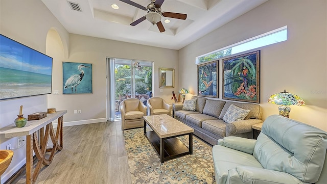 living area with visible vents, a ceiling fan, coffered ceiling, light wood finished floors, and baseboards