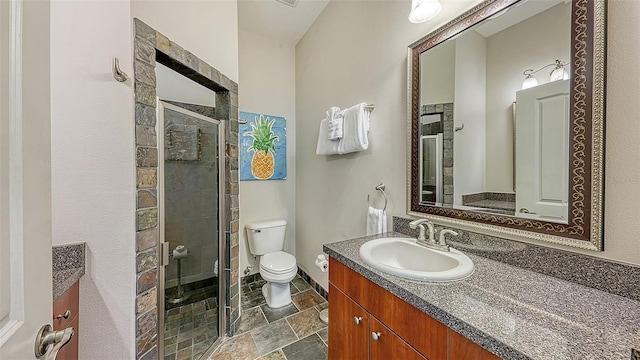 bathroom featuring stone tile flooring, a stall shower, toilet, and vanity