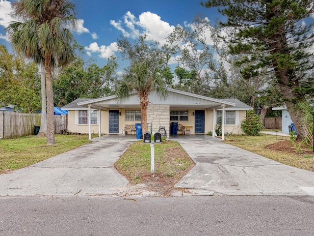 single story home with a carport, a front lawn, stone siding, and driveway