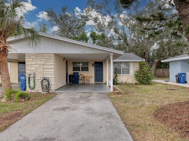 ranch-style home with stone siding, a front yard, concrete driveway, and an attached carport