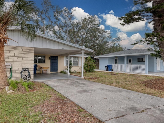 view of front of property with a carport, driveway, a front lawn, and stucco siding