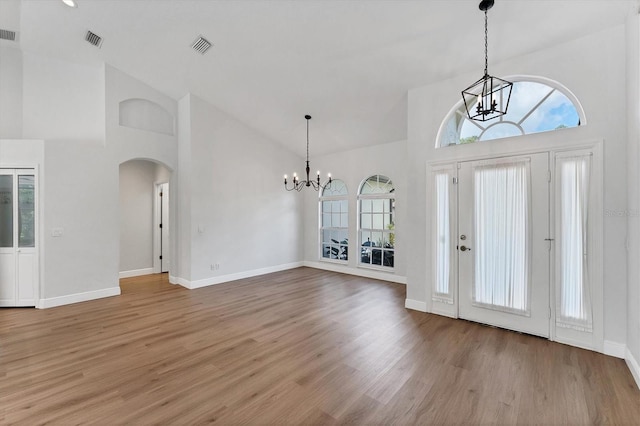 foyer entrance with an inviting chandelier, high vaulted ceiling, and hardwood / wood-style flooring