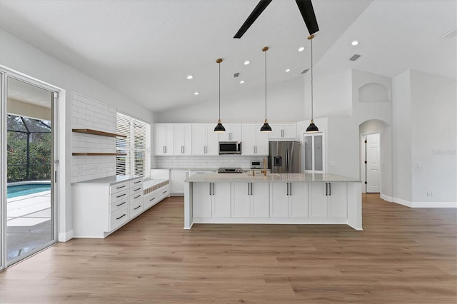 kitchen with appliances with stainless steel finishes, decorative light fixtures, white cabinetry, ceiling fan, and a center island with sink