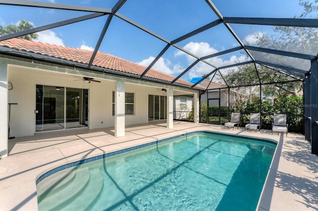 view of swimming pool with a patio area, ceiling fan, and glass enclosure