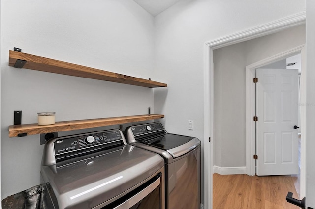 washroom featuring washing machine and clothes dryer and light hardwood / wood-style flooring