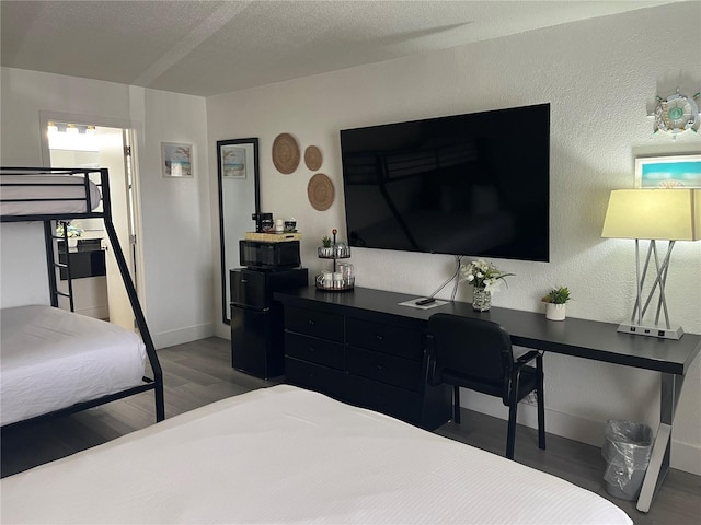 bedroom featuring freestanding refrigerator, dark wood finished floors, a textured ceiling, and baseboards