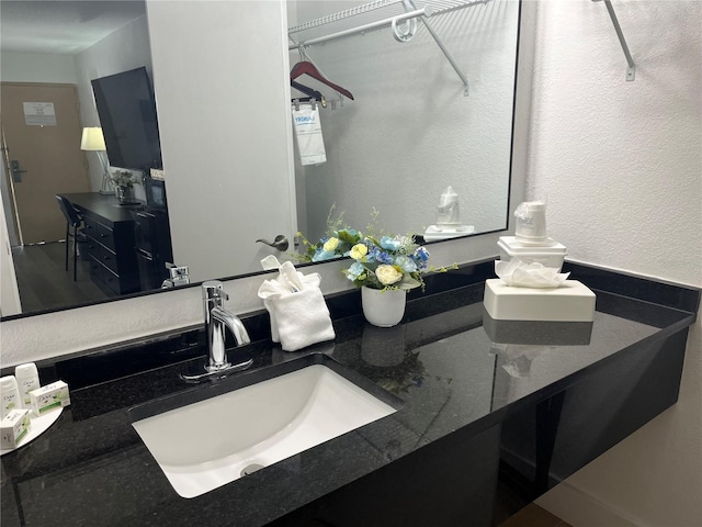 full bathroom featuring a textured wall and vanity