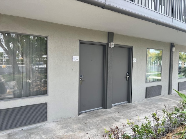 view of exterior entry featuring a patio area, visible vents, and stucco siding