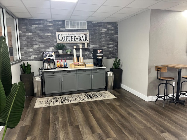 bar with dark wood-style flooring, a drop ceiling, visible vents, and baseboards