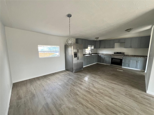 kitchen with gray cabinets, appliances with stainless steel finishes, dark hardwood / wood-style floors, pendant lighting, and sink