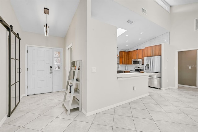 foyer featuring a barn door, light tile patterned floors, and high vaulted ceiling