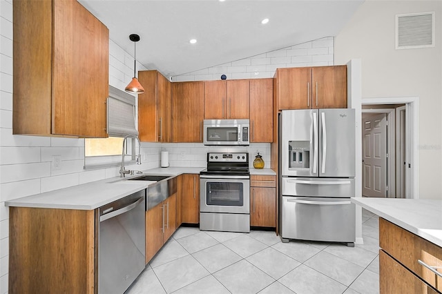 kitchen featuring lofted ceiling, stainless steel appliances, decorative light fixtures, sink, and decorative backsplash