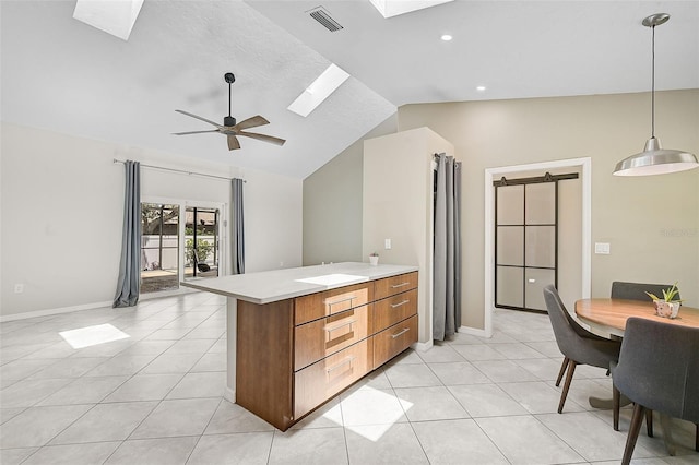 kitchen with vaulted ceiling with skylight, ceiling fan, pendant lighting, light tile patterned floors, and kitchen peninsula