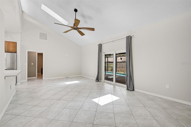 empty room with ceiling fan, light tile patterned flooring, high vaulted ceiling, and a skylight