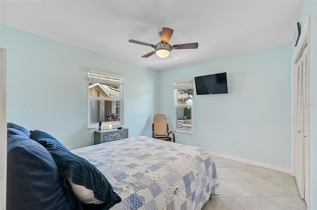 tiled bedroom with ceiling fan and a closet