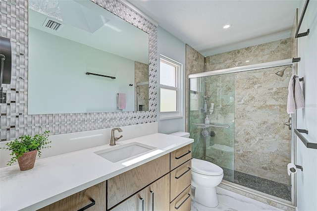 bathroom with backsplash, vanity, toilet, and a shower with door