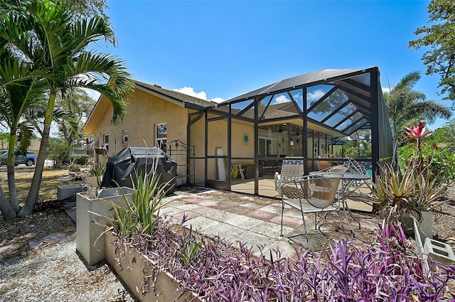 back of house with ceiling fan, glass enclosure, and a patio area