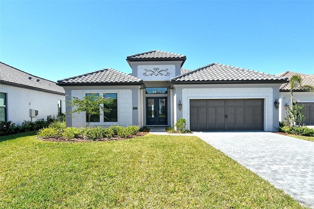 mediterranean / spanish home with an attached garage, a front lawn, decorative driveway, and french doors