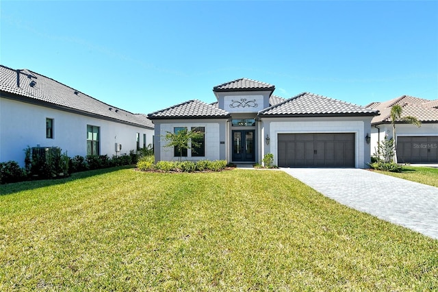 mediterranean / spanish house with an attached garage, a front lawn, french doors, a tile roof, and decorative driveway