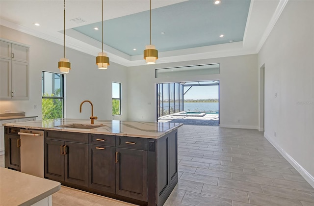 552 Bocelli Dr, North Venice, FL 34275 - kitchen with a water view, a kitchen island with sink, a sink, a raised ceiling, and hanging light fixtures