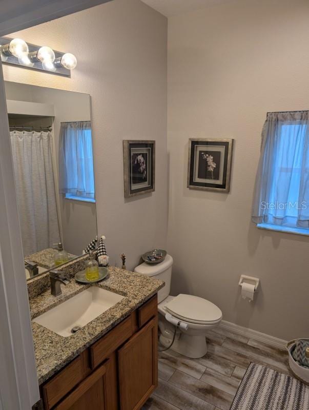 bathroom with vanity, toilet, and wood-type flooring