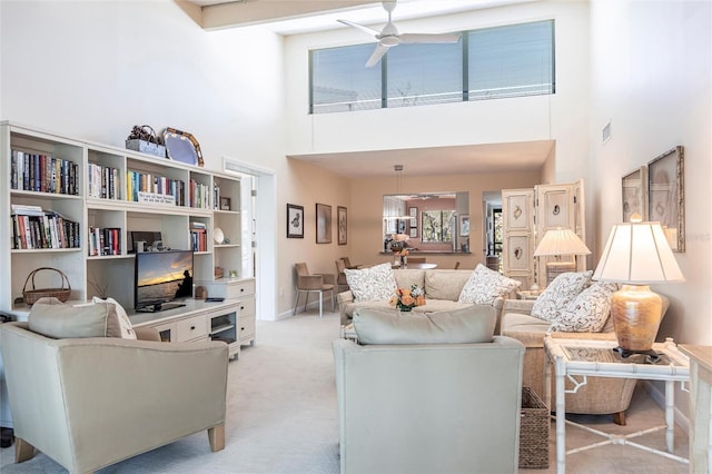 living room featuring light carpet, ceiling fan, and a high ceiling