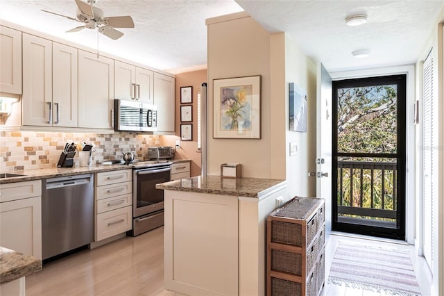 kitchen featuring white cabinets, stainless steel appliances, a wealth of natural light, and stone counters