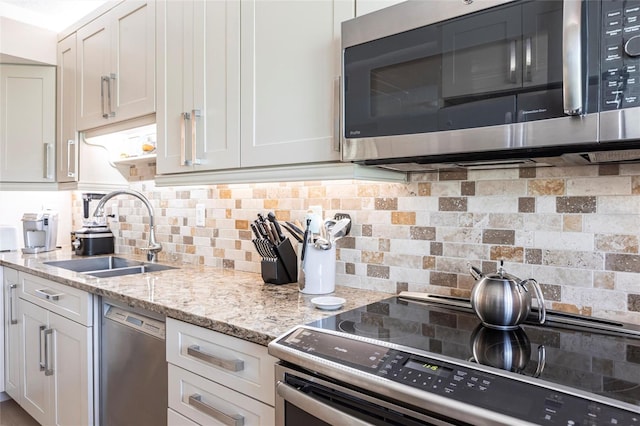 kitchen featuring light stone counters, sink, stainless steel appliances, and white cabinets