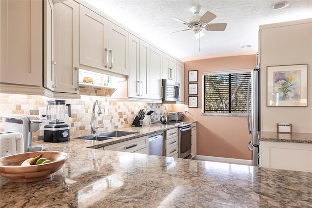 kitchen with light stone counters, sink, tasteful backsplash, and stainless steel appliances