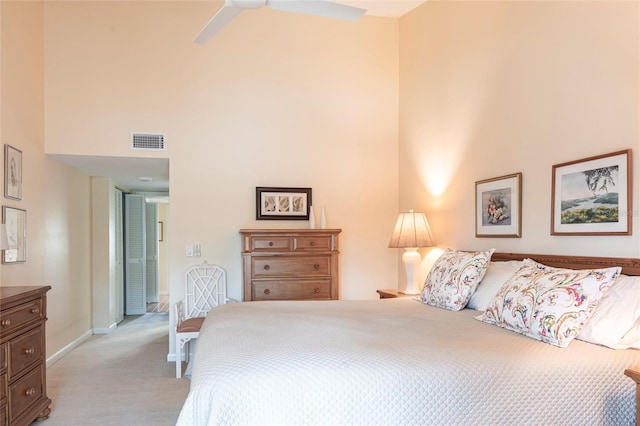 carpeted bedroom with ceiling fan and a high ceiling