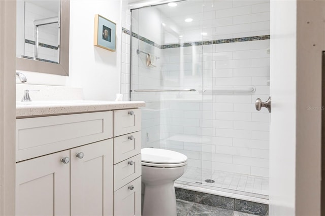 bathroom featuring vanity, a shower with door, and toilet