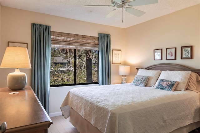 bedroom featuring ceiling fan, a textured ceiling, and light wood-type flooring