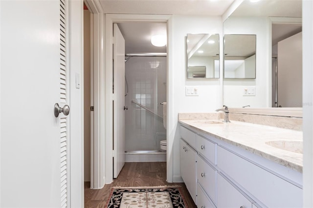 bathroom featuring vanity, hardwood / wood-style floors, a shower with shower door, and toilet