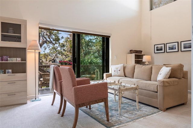 living room featuring a towering ceiling and light colored carpet