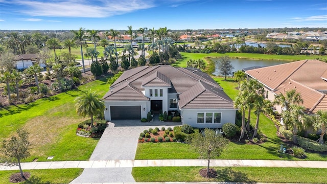 view of front of house with decorative driveway, a tile roof, a water view, a front yard, and a garage