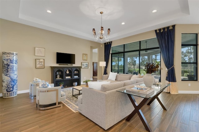 living room with a tray ceiling and wood finished floors