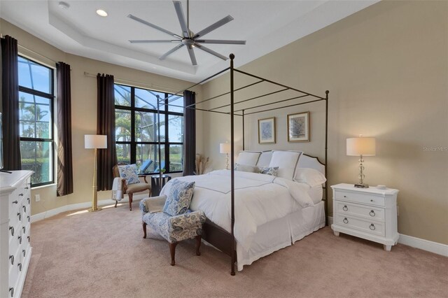 bedroom featuring light carpet, baseboards, a raised ceiling, and recessed lighting