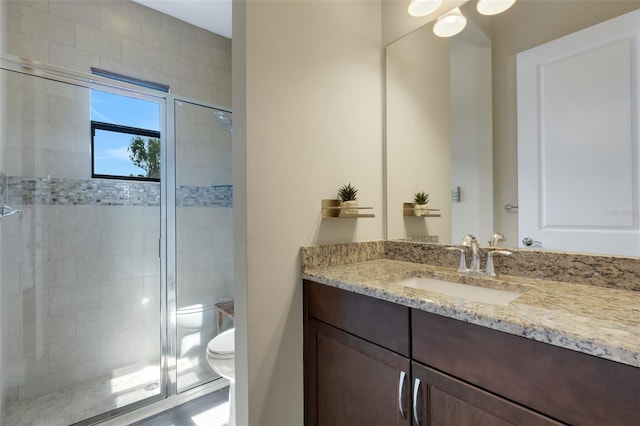 bathroom with vanity, a shower stall, and toilet