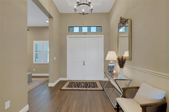 foyer entrance featuring baseboards, dark wood finished floors, and a notable chandelier