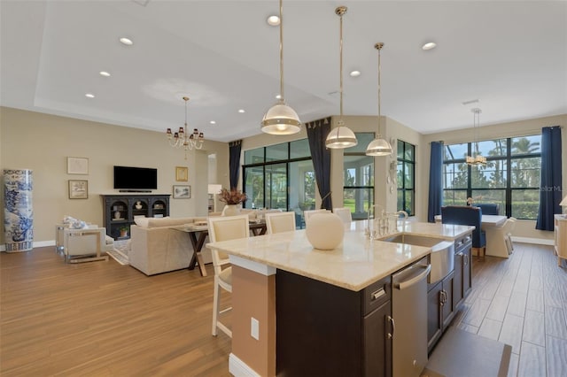 kitchen featuring pendant lighting, open floor plan, an island with sink, a chandelier, and dishwasher