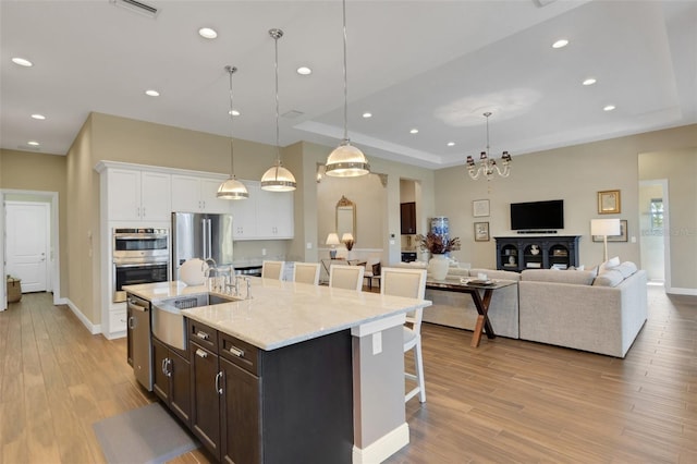 kitchen with appliances with stainless steel finishes, a kitchen bar, decorative light fixtures, and white cabinets